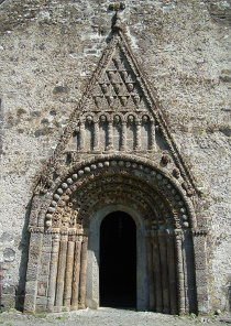 [Image:Extremely elaborate stone church entrace, with mutiple decorative arches, over which is a peaked design featuring human heads and other motifs]